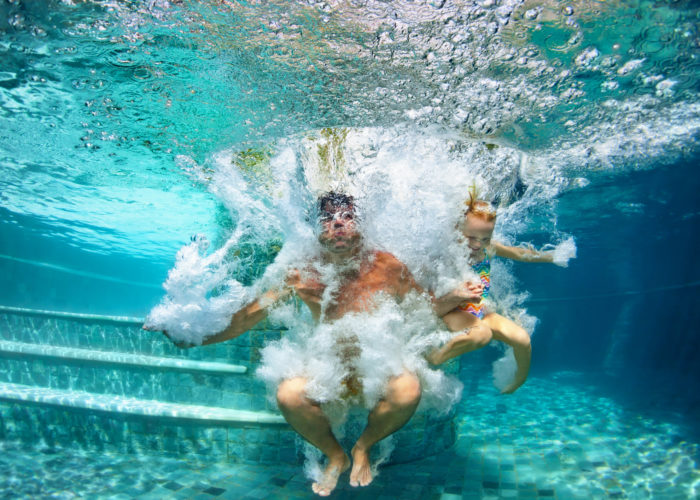 Happy family diving underwater with fun in swimming pool Happy family diving underwater with fun in swimming pool