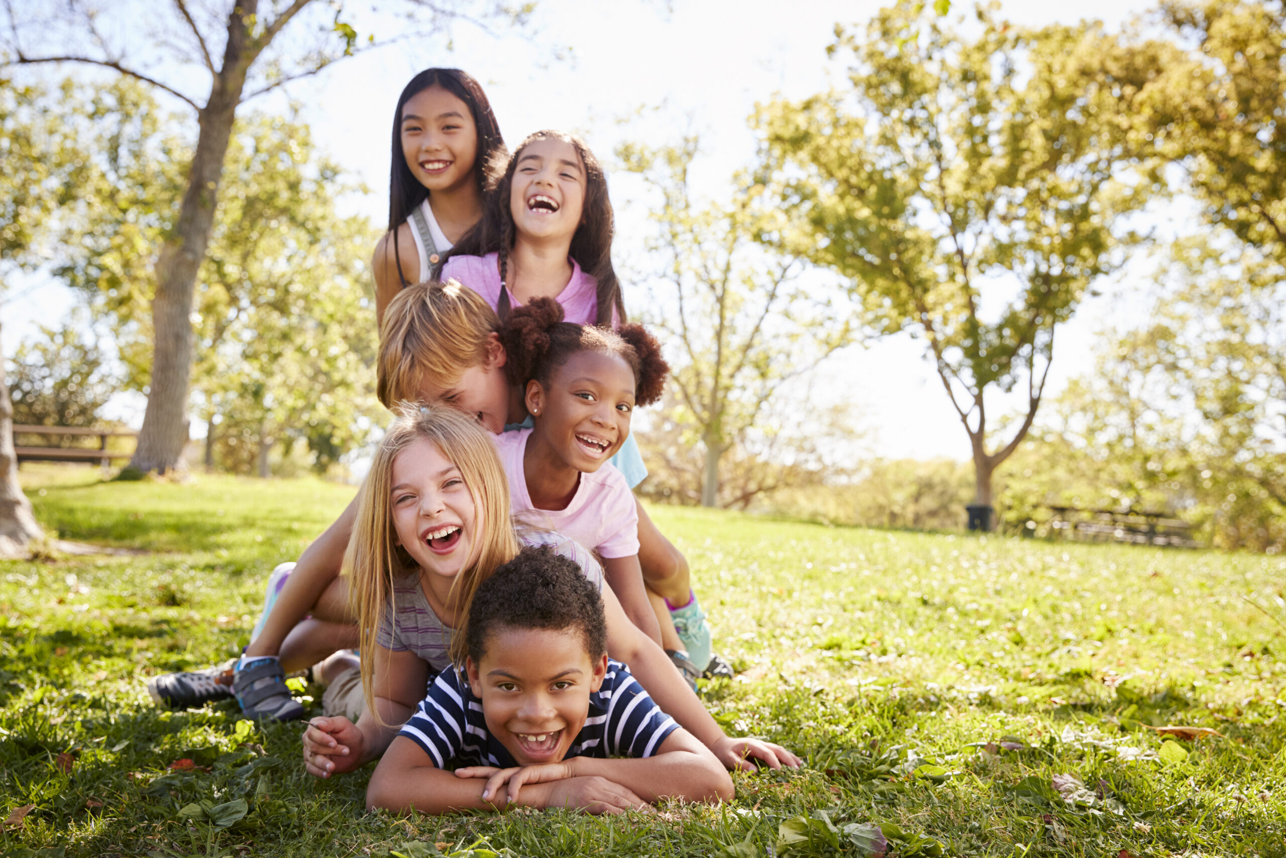Multi-ethnic group of children lying in a pile in a park
